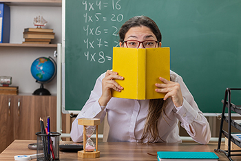 picture of a teacher holding a book against her face